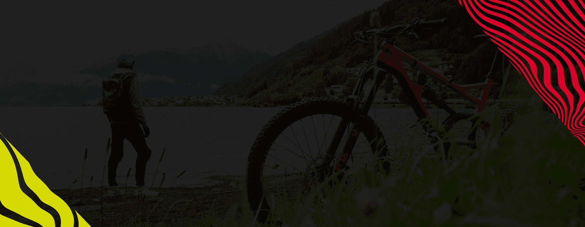 Ciclista ao lado da mountain bike, à beira de um lago, ao anoitecer
